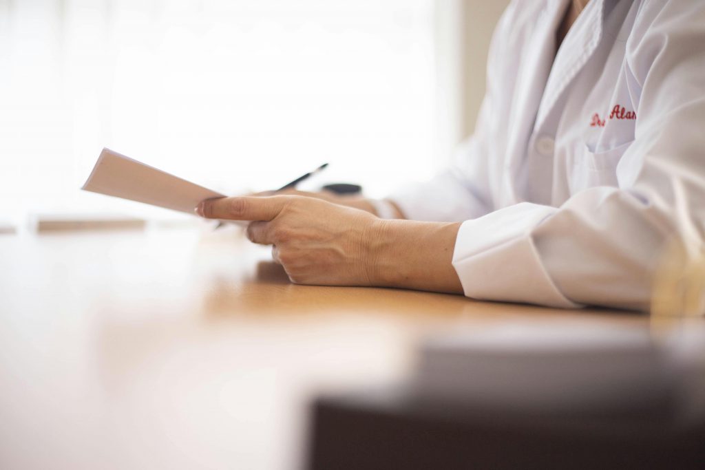 Our Resources Close-up of a doctor in a lab coat reviewing paperwork at a desk.