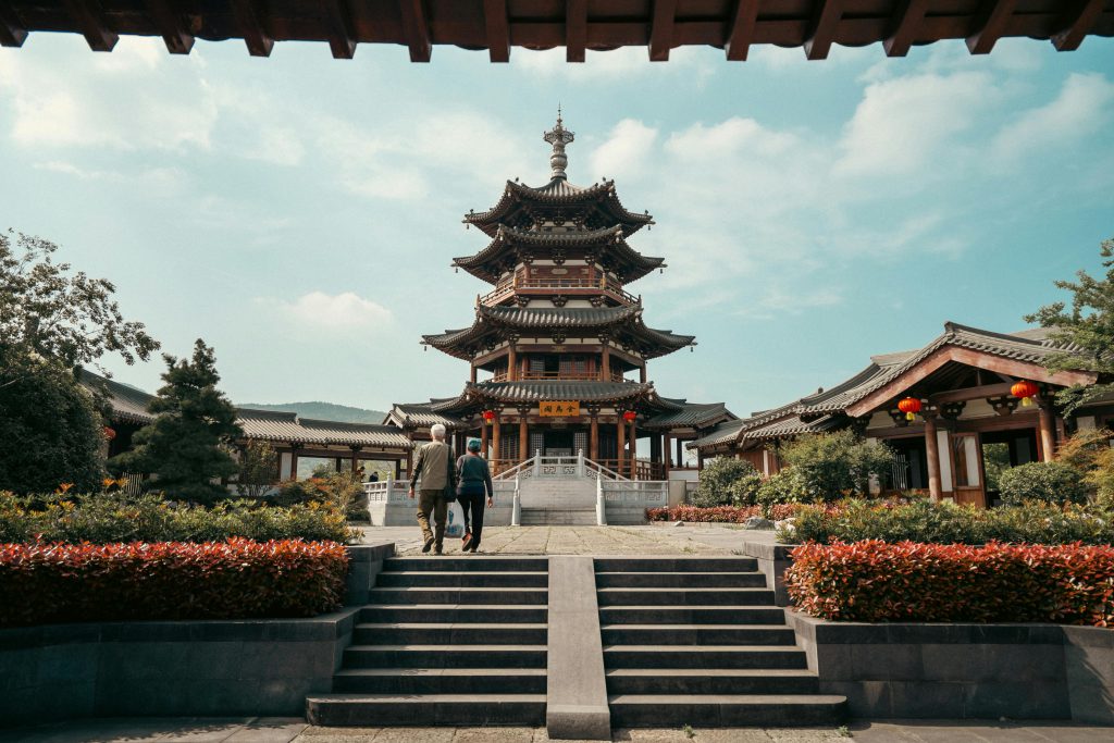 Photograph of the Jin Wu Pavilion in Nanjing, showcasing traditional Chinese architecture with two people walking towards it.