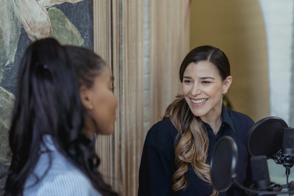 Dental Implants A candid moment of two women chatting during a podcast recording session.